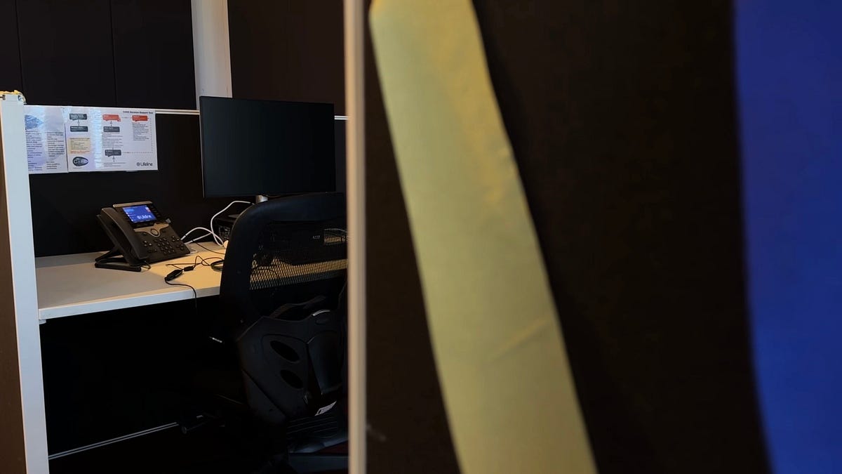 Photo of the volunteer office for Lifeline, where there is a phone on a desk with guidance for call takers pinned above it.